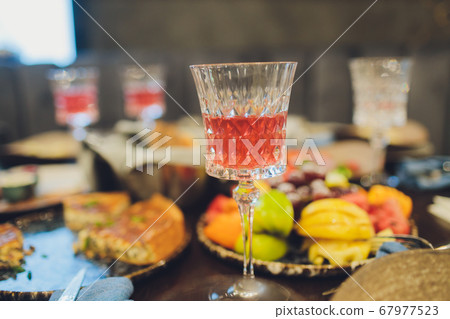 Focus on hands serving dishes of meat and vegetables to a group of friends gathered around a table on a summer terrace. 67977523
