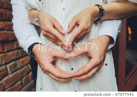 Closeup of couple making heart shape with hands. Closeup of couple making heart shape with hands. 67977541