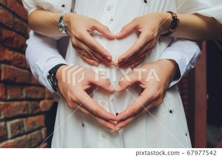 Closeup of couple making heart shape with hands. 67977542
