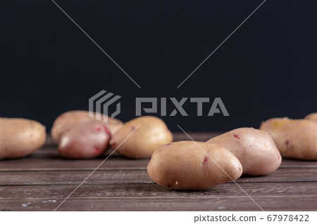 Fresh potatoes on the wood background. creative photo. 67978422