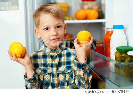 Little boy standing in front of open fridge and choosing food 67978424