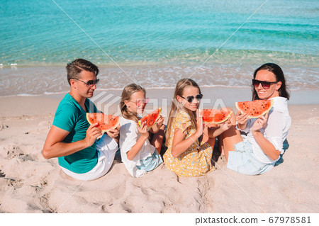 Happy family eating watermelon on the beach. Happy family eating watermelon on the beach. 67978581