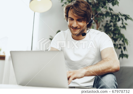 Young man businessman with headset working on laptop from home 67978732