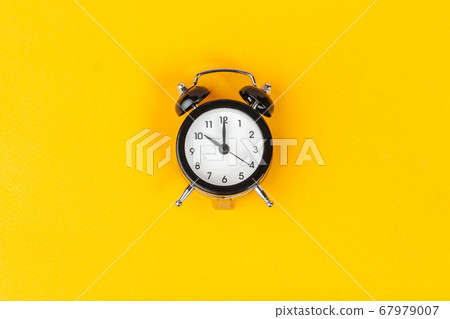 Alarm clock on bright yellow background close up Alarm clock on bright yellow background close up 67979007