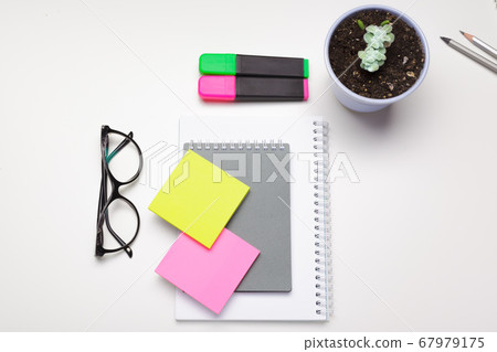 Sticky notes with markers, colored pens, paper clips laying on a table 67979175