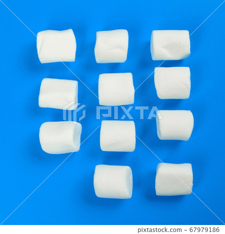 marshmallow laid out on blue paper background. pastel creative textured pattern. marshmallow laid out on blue paper background. pastel creative textured pattern. 67979186