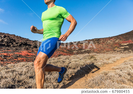 Trail runner ultra running man athlete on desert path in dry heat landscape. Male sports person training outdoors. Closeup of body and legs. 67980455