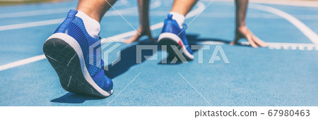 Sprinter waiting for start of race on running tracks at outdoor stadium. Sport and fitness runner man athlete on blue run track with running shoes. Banner panorama. Sprinter waiting for start of race on running tracks at outdoor stadium. Sport and fitness runner man athlete on blue run track with running shoes. Banner panorama. 67980463