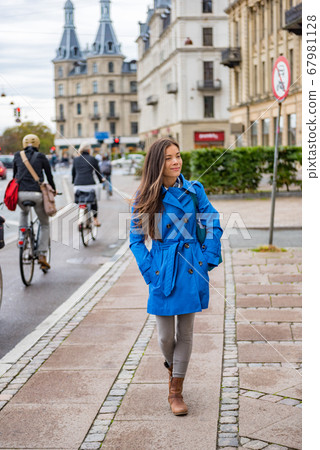 Asian tourist woman walking in Copenhagen city street next to bike path, modern commute. Urban living lifestyle young happy person commuting in fall or spring. Asian tourist woman walking in Copenhagen city street next to bike path, modern commute. Urban living lifestyle young happy person commuting in fall or spring. 67981128