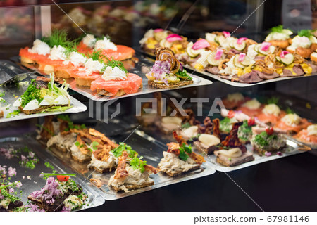 Danish smorrebrod traditional open sandwich at Copenhagen food market store. Many sandwiches on display with seafood and meat, smoked salmon. 67981146