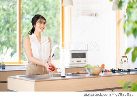 在明亮的廚房裡做飯的年輕女子 67983053