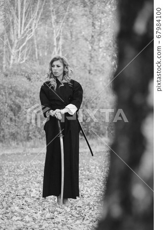 European woman with a katana in a kimono. the girl trains martial arts. a woman in the autumn forest. a warrior with a cold weapon in his hands 67984100