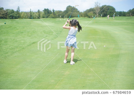 Back view of a first grade elementary school girl enjoying putting golf at a leisure spot Back view of a first grade elementary school girl enjoying putting golf at a leisure spot 67984659