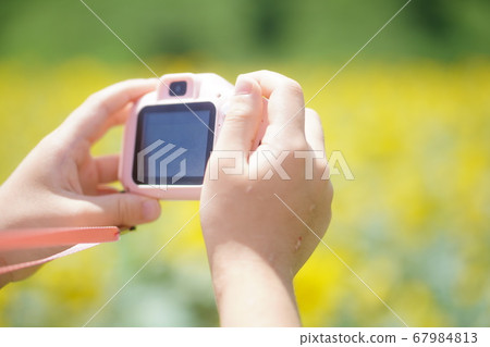 A first grade elementary school student enjoys taking pictures with a kids camera. 67984813