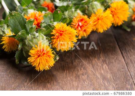 Close up of safflower flowers on the dark brown table 67986380