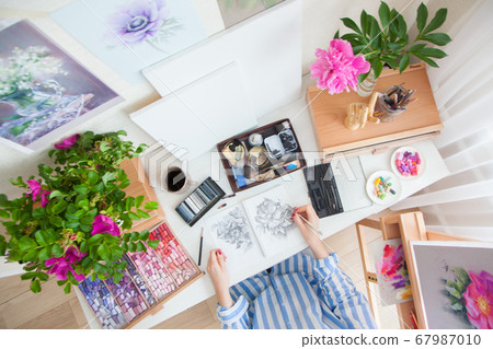 Top view girl artist draws a sketch of rose hip flowers sitting at her workplace Top view girl artist draws a sketch of rose hip flowers sitting at her workplace 67987010