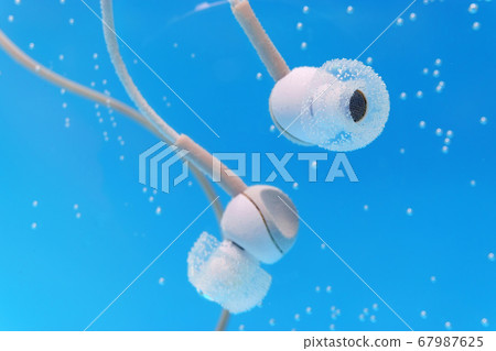 Headphones under water on blue background. 67987625