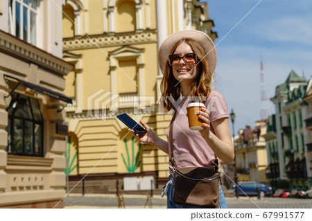 Beautiful Young Woman tourist with takeout coffee in the City Center talking on the phone Beautiful Young Woman tourist with takeout coffee in the City Center talking on the phone 67991577