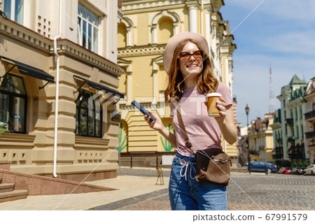 Beautiful Young Woman tourist with takeout coffee in the City Center talking on the phone Beautiful Young Woman tourist with takeout coffee in the City Center talking on the phone 67991579