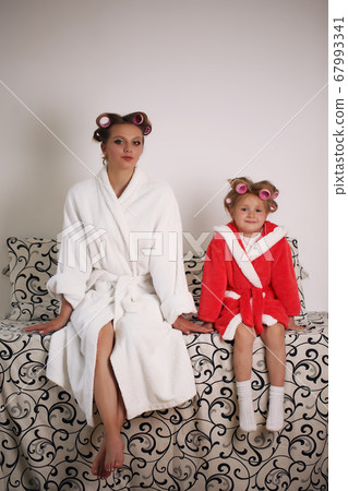 Photo of mother and daughter in white coats. They are sitting on the couch 67993341