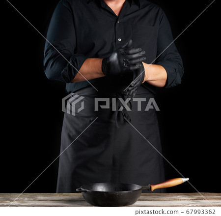 chef in black shirt and apron puts black latex 67993362
