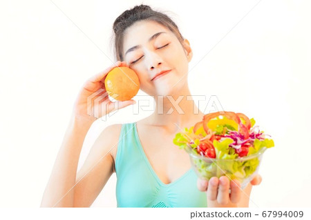 Young beautiful asian woman wore blue undershirt, Holding a salad glass cup and orange isolated on white background  67994009