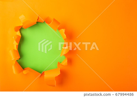 Torn hole and ripped of orange paper 67994486