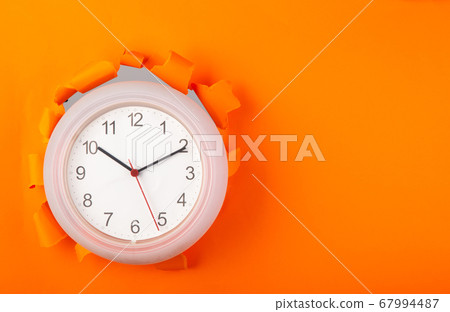 clock showing up from torn orange paper 67994487