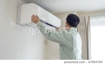 Worker installing an air conditioner 67994709
