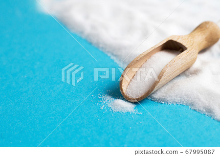 Salt grain in wooden spoon top view on blue background 67995087