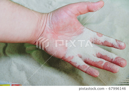 The man takes the white sand with his hand The man takes the white sand with his hand 67996146