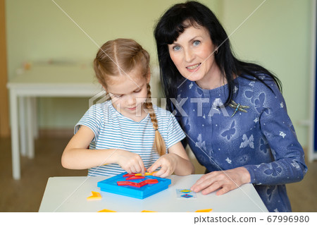 a teacher and girl solve mathematical puzzle. a teacher and girl solve mathematical puzzle. 67996980