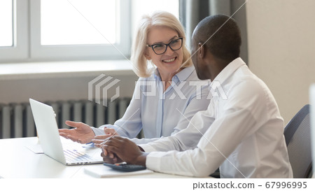 Smiling mature businesswoman coach training African American employee 67996995
