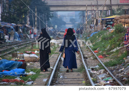 Dhaka, Bangladesh A Muslim woman walking along the railroad market along the railroad and trash scattered on the railroad 67997079