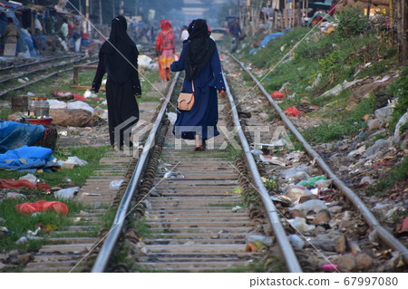 孟加拉國達卡一名穆斯林婦女沿著鐵路市場走，沿著鐵路走，垃圾散落在鐵路上 67997080