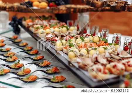 Different light snack on glass and wooden tray Different light snack on glass and wooden tray 68002122