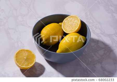 sliced and whole lemons on a white table and in sliced and whole lemons on a white table and in 68002233