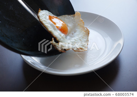 Fried egg and transfer from frying pan to plate with gold Fried egg and transfer from frying pan to plate with gold 68003574