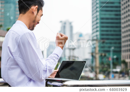 Young businessman excited raise hand up be glad 68003929