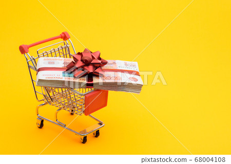On the grocery cart is a bundle of money as a gift 68004108