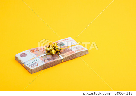On a yellow background lies a bundle of notes with 68004115