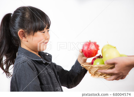 The picture of a child holding a red and green apple 68004574