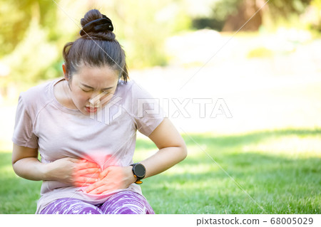 Asian Woman's stomach aches exercising while woman running  68005029