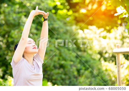 young Asian woman doing yoga fitness exercises in the nature park,  68005030