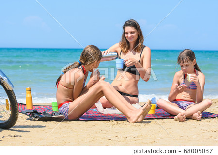 Mom pours tea from a thermos, children eat cooked 68005037