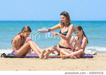 Mom pours tea from a thermos, having lunch on the 68005038