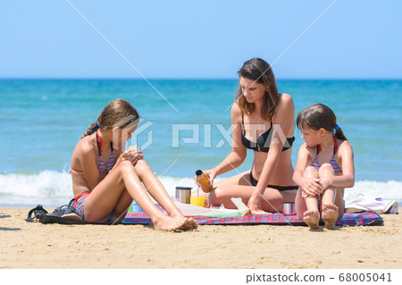 Family having a snack while sitting on a rug on Family having a snack while sitting on a rug on 68005041