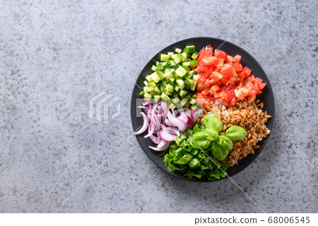 Salad of whole grain cereal spelt with vegetables, tomato, cucumber, greens on grey stone table with space for text. Salad of whole grain cereal spelt with vegetables, tomato, cucumber, greens on grey stone table with space for text. 68006545