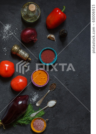Raw vegetables and bright spices on a black table on top 68006915