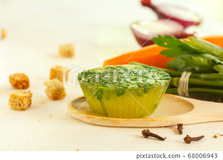 Frozen green broth in the form of a cake and ingredients for cooking. Horizontally with space 68006943